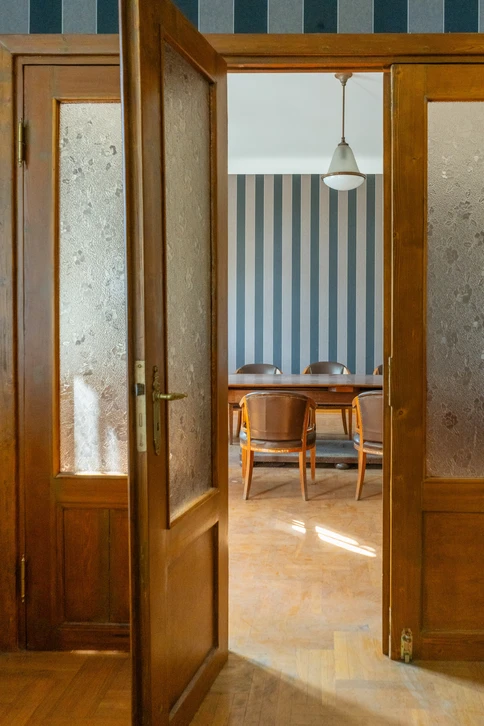 Intérieur professionnel d'un immeuble collectif ou bâtiment commercial montrant une ou plusieurs portes intérieures en bois de qualité, aux finitions soignées et aux proportions généreuses, illustrant la menuiserie professionnelle sur mesure. Les portes doivent être visibles et bien mises en valeur, avec un contexte architectural moderne et épuré reflétant un environnement professionnel (couloirs, espaces de circulation, cloisons légères). Photographie de qualité professionnel, lumière naturelle ou bien équilibrée.