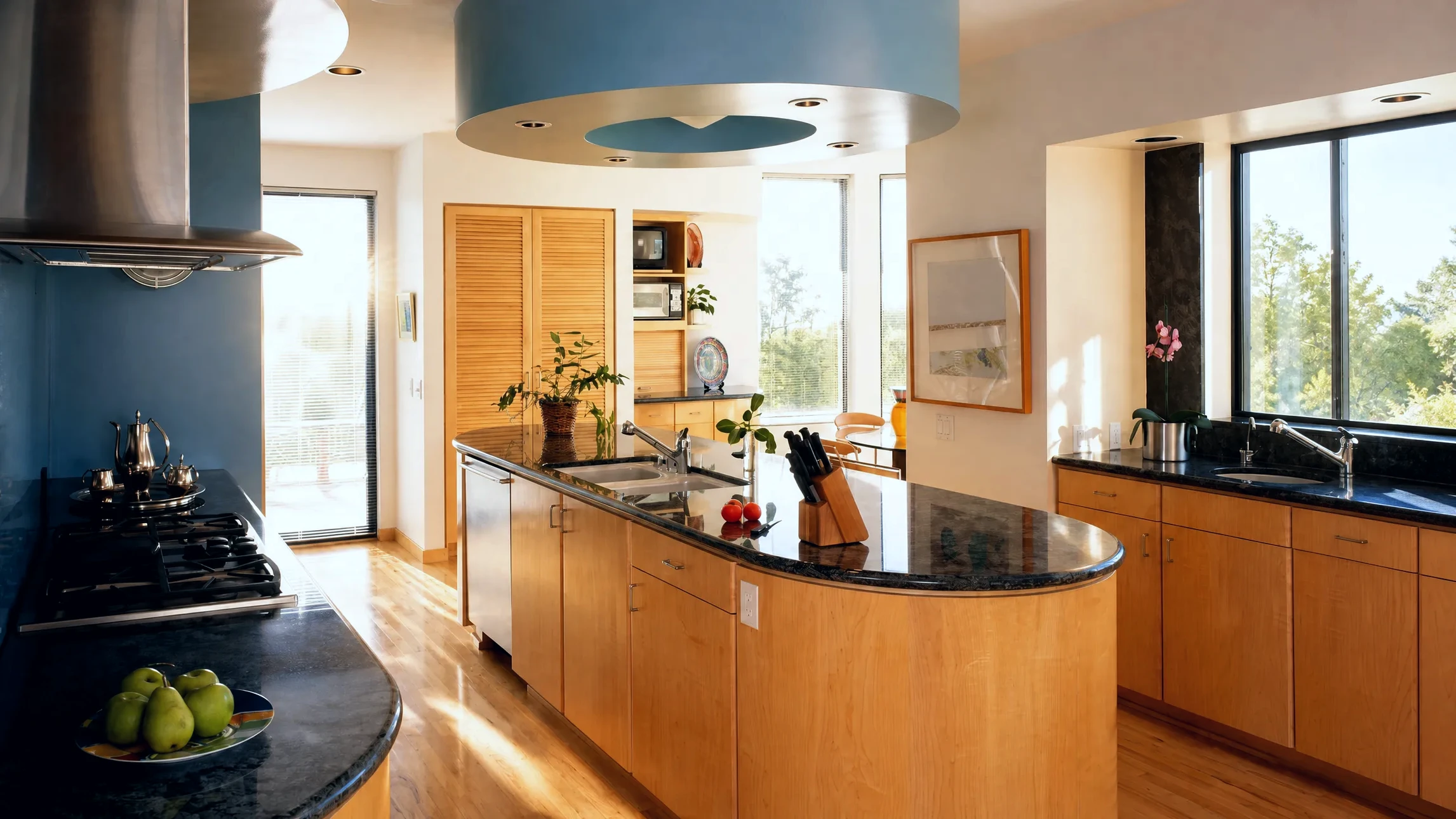 Cuisine moderne avec façade en bois clair, îlot central intégrant évier et four encastrable