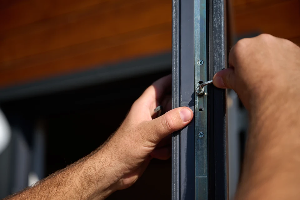 Porte d'entrée en bois teinté orange avec serrure de sécurité multipoints visible sur chant