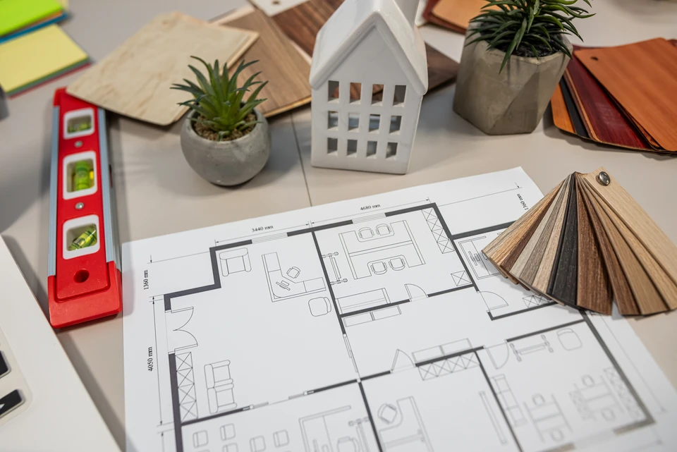 Photographie d'un atelier de menuiserie bois montrant une équipe de 3 à 4 menuisiers professionnels en tenue de travail, concentrés sur différentes étapes de leur activité : l'un travaille sur une pièce bois à l'établi, un autre utilise une machine de découpe, un troisième examine ou mesure un élément. L'arrière-plan montre un atelier bien organisé avec des outils professionnels, du bois rangé, une ambiance de travail sérieuse et structurée. Lumière naturelle ou de bon professionnel. Aucun sourire artificiel ni pose, juste des collaborateurs concentrés sur leur métier.